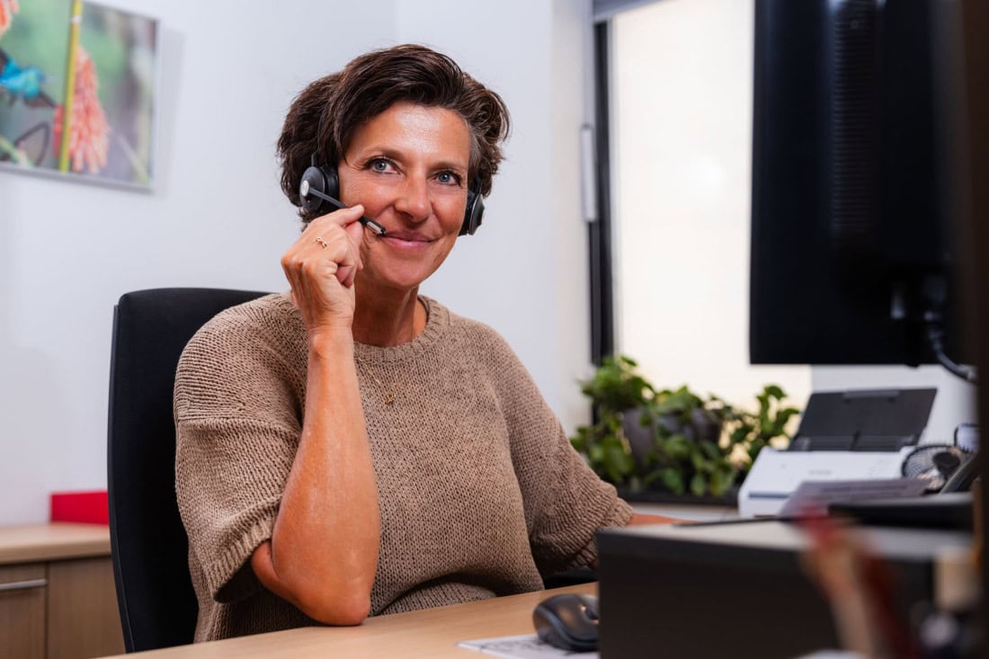 Call GP? Woman with headset works in office, customer service or medical assistance.