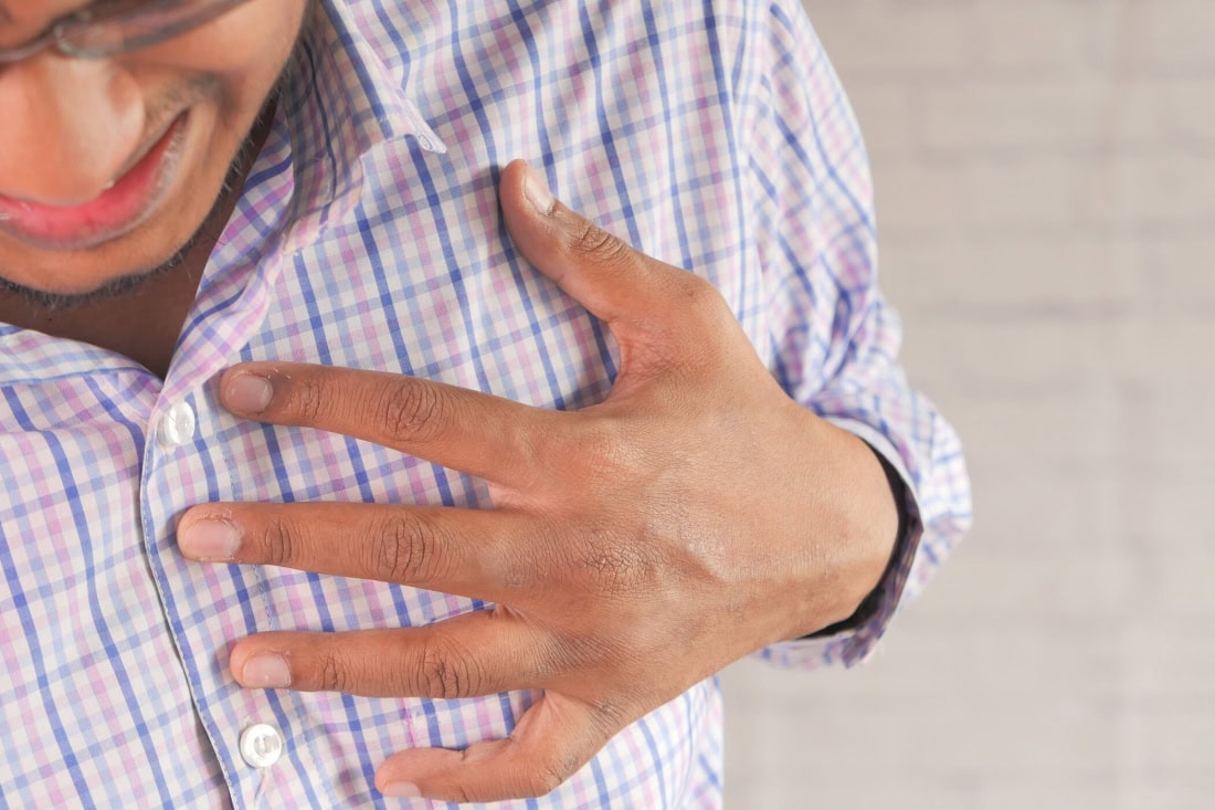 Cardiovascular disease: man holds hand on chest, healthcare and heart problems, close-up.